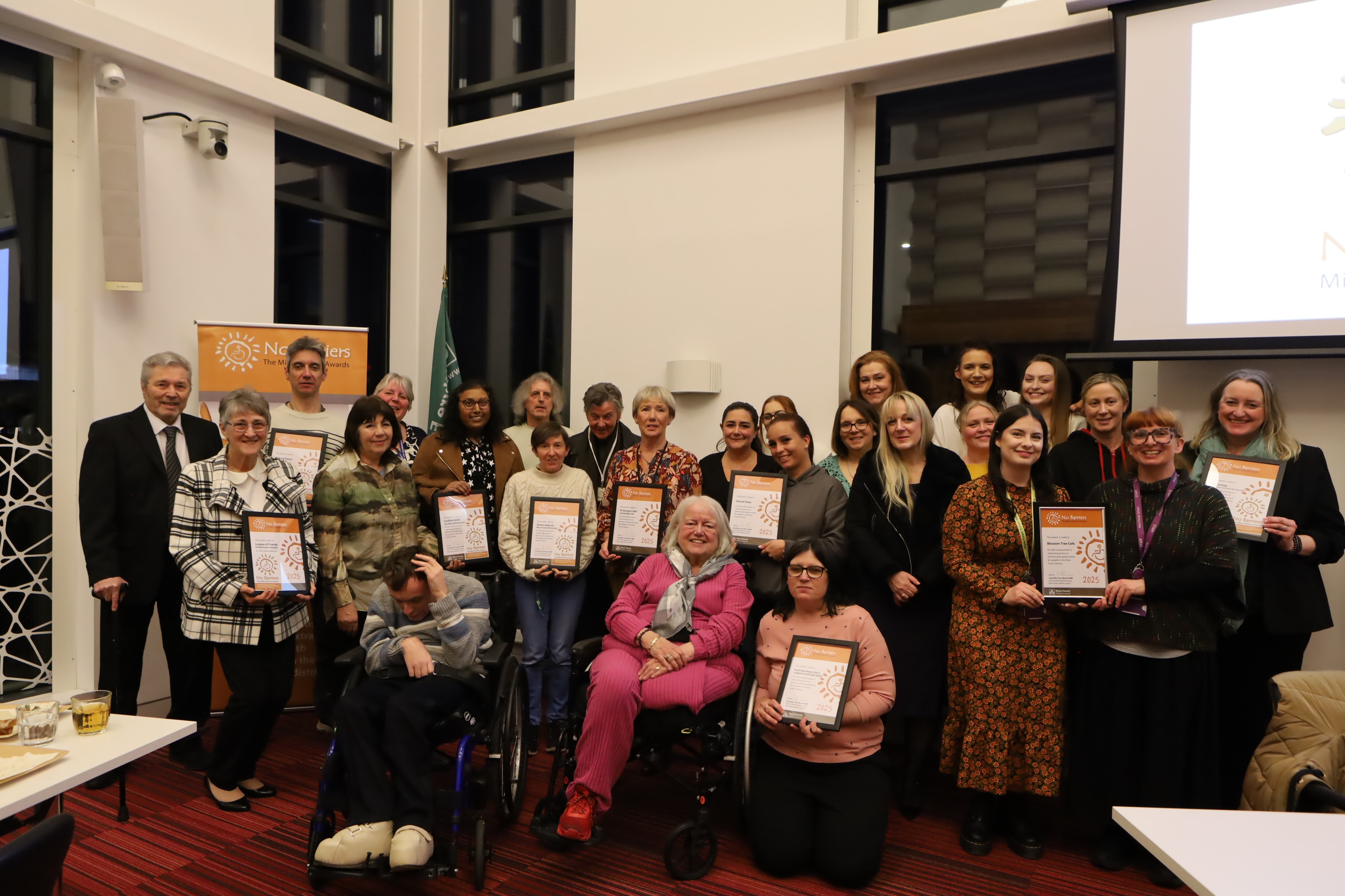 Group of people holding certificates and surrounding a lady in a wheelchair.