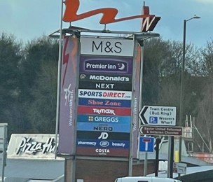 large retail park sign with multiple shop signs