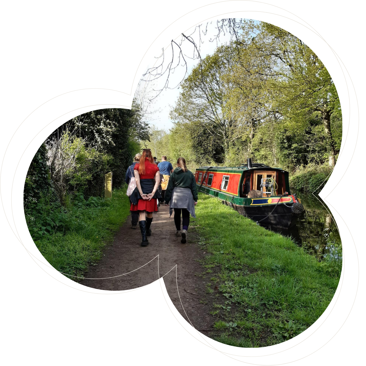 two people walking down a canal path with a canal boat to the right
