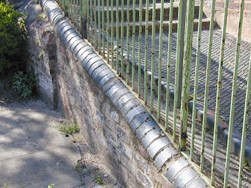 brick wall with rounded top and green railings along top