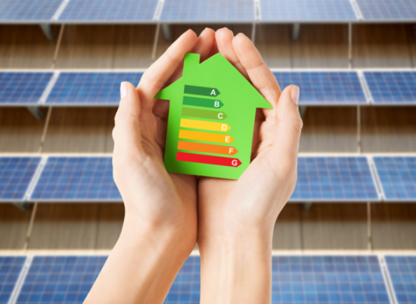 Hands holding a housing warmth scale with solar panels on building behind.