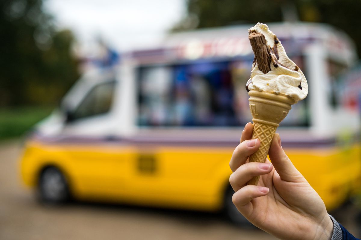 An ice cream with an ice cream van in the background