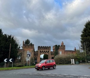 car on road in front of gateway with castellations