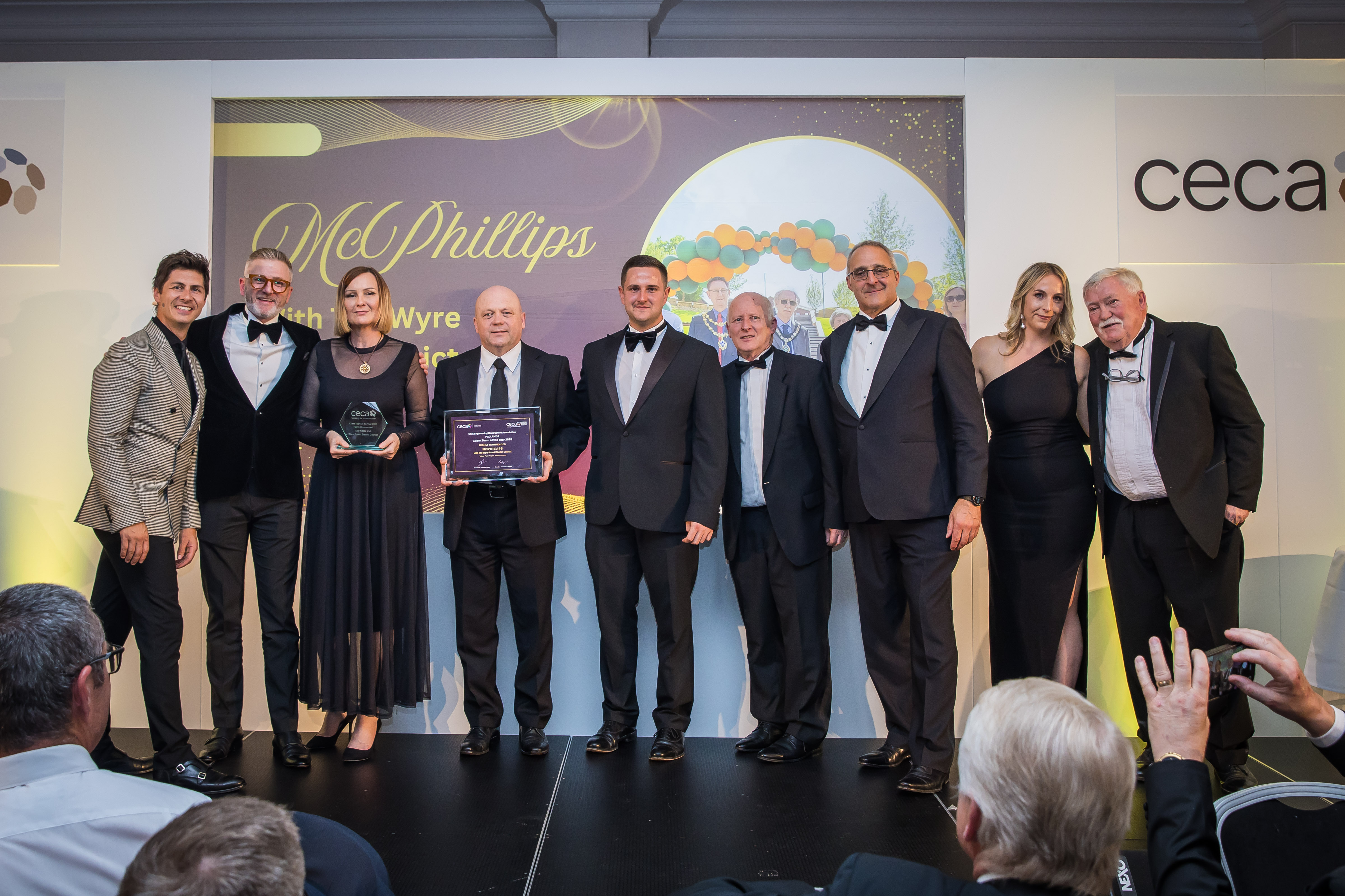 A group of people in formal wear on stage at an awards ceremony