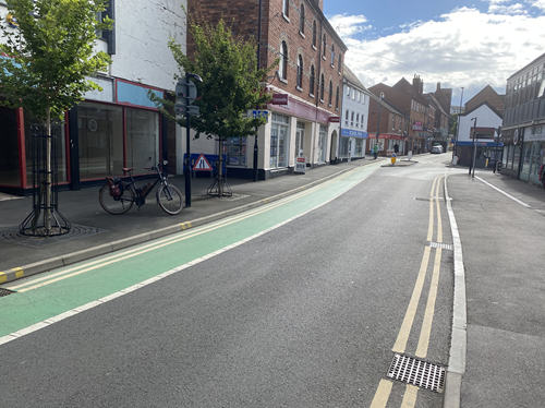 view down road and cycle path with shops either side