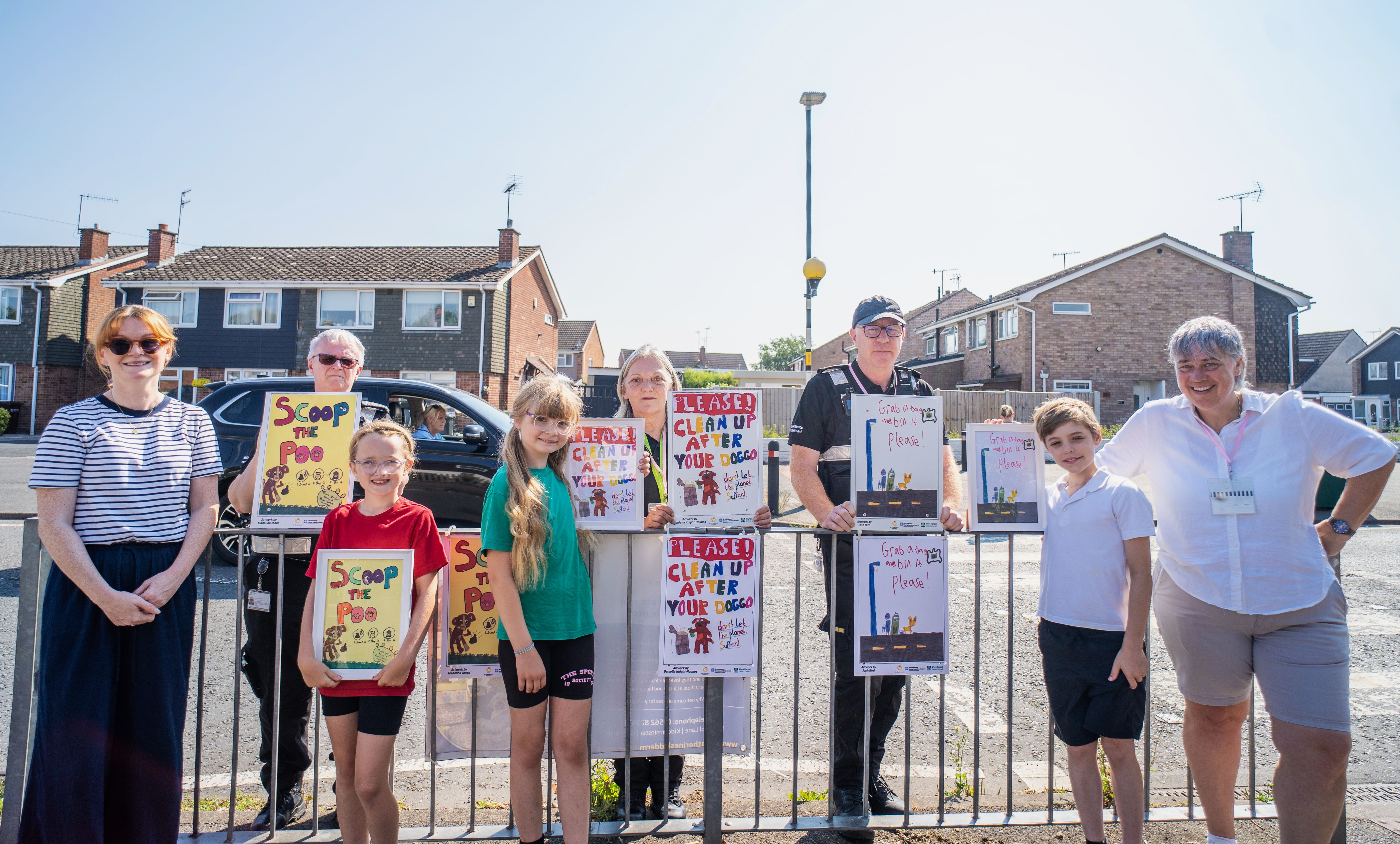 A group of children and adults outside a school holding posters
