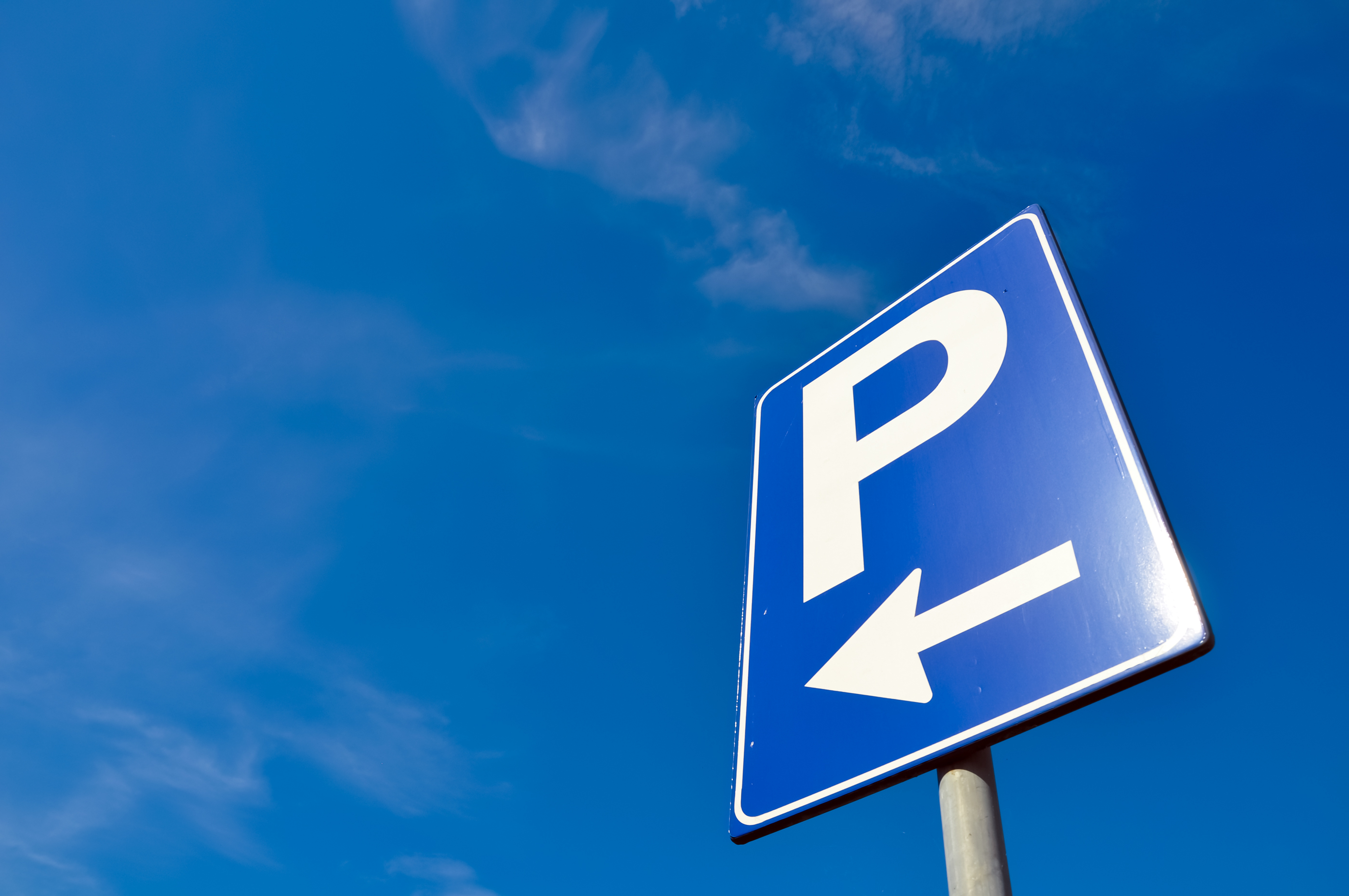 Blue sign with a white P and white arrow on it. It is against a blue sky